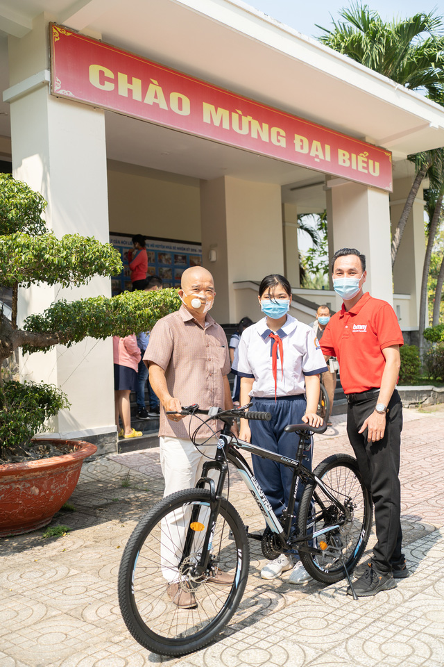 Ông Phan Thế Hùng, Trưởng phòng Kinh Doanh miền Nam Công ty Cổ phần Điện tử Benny Việt Nam chụp ảnh cùng một em học sinh đến nhận xe đạp.